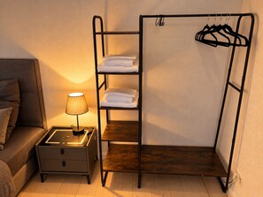 A bunk bed with a shelf and a hanging rack, a bedside table with a lamp, and a sofa. - Elbflorenz Familien Loft (Dresden)