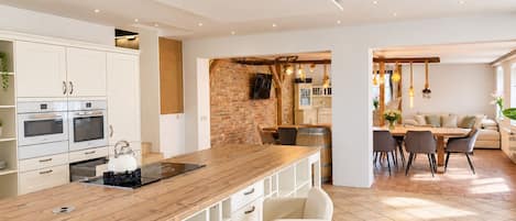 A modern kitchen with white cabinetry, a wooden countertop, and a dining area with a table and chairs.