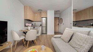 A modern kitchen with wooden cabinets, a stainless steel refrigerator, and a dining area with a table and chairs.