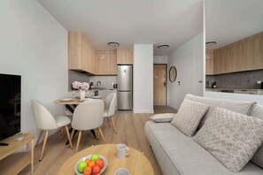 Eine moderne Küche mit Holzausstattung, einem Edelstahlkühlschrank und einem Essbereich mit Tisch und Stühlen.