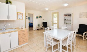 A clean, well-lit kitchen with white cabinets, a dining table, and chairs. There is a small window providing natural light. - Villa in Marina Di Ragusa with 3 bedrooms sleeps 7 (Marina Di Ragusa)