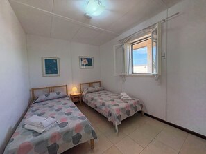 A room with two single beds, a small table with a lamp, and a window with a view. - Villa in Marina Di Ragusa with 3 bedrooms sleeps 7 (Marina Di Ragusa)