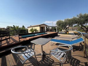 A poolside area with a pool, lounge chairs, and a small building. - Villa in Marina Di Ragusa with 3 bedrooms sleeps 7 (Marina Di Ragusa)