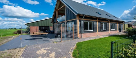 A modern building with a sloped roof, large windows, and a paved entrance area.