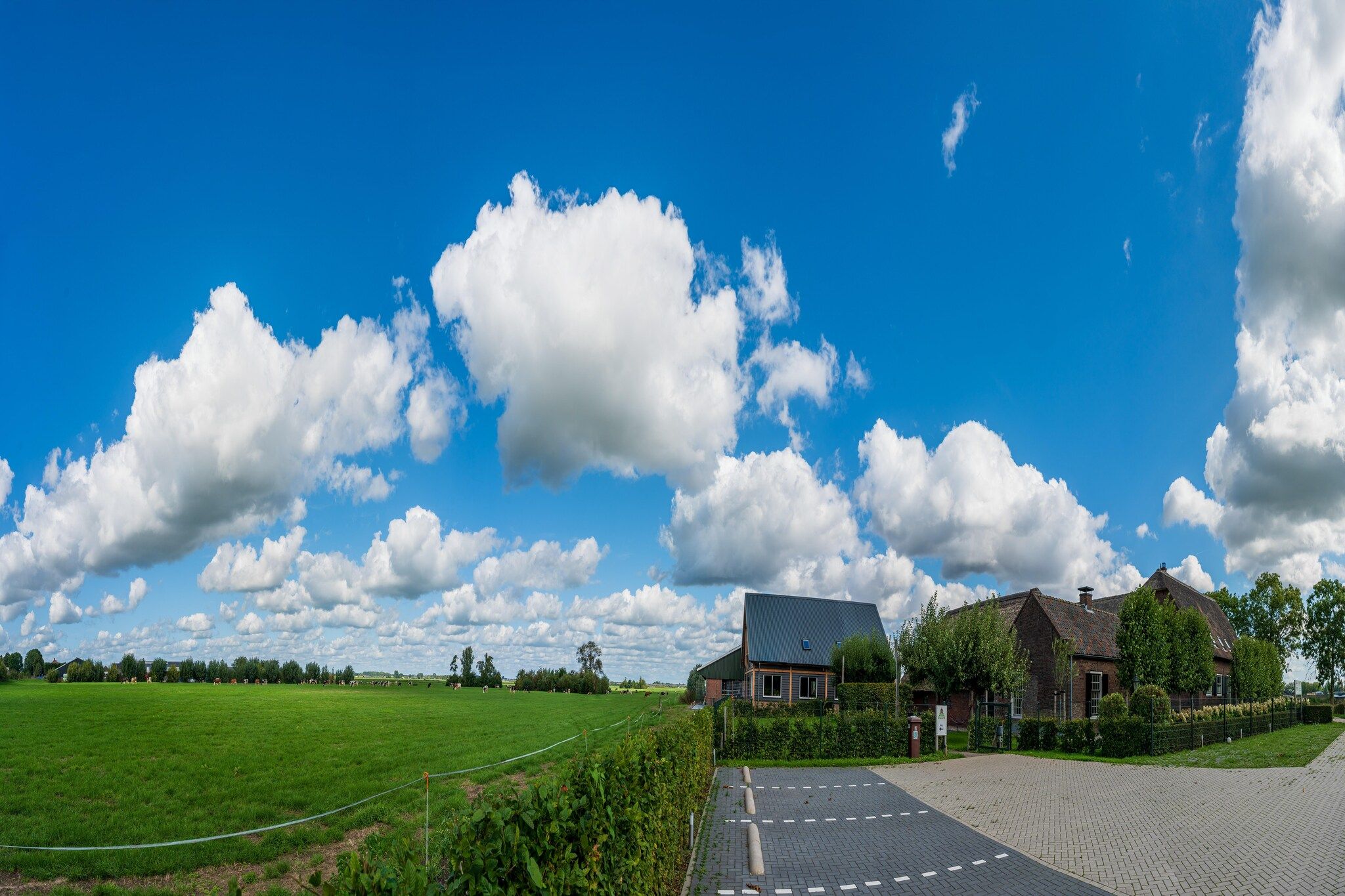 Paisagem rural com uma casa, campos abertos e um céu azul límpido.