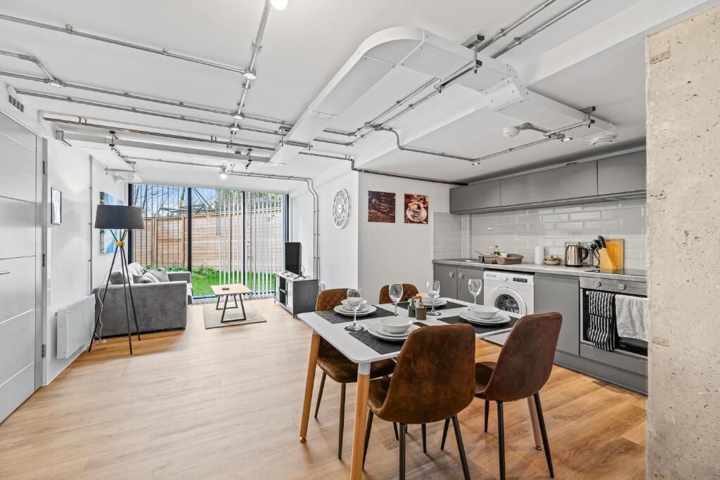 A modern kitchen with grey cabinets, a built-in oven, and a dining area with a table set for four.
