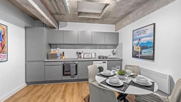 A modern kitchen with grey cabinets, a dining area with a table set for two, and a poster on the wall.