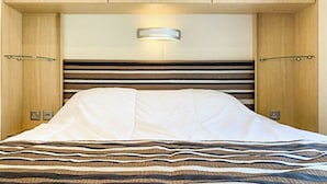 A bed with a striped bedspread, wooden headboard, and bedside lamps.