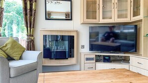 A modern living room with a sofa, a TV, a glass cabinet, and a wooden coffee table.