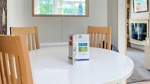 A round white table with four wooden chairs, a box on the table, and a window in the background.