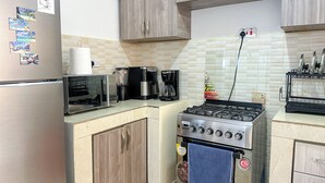 A kitchen with a refrigerator, microwave, coffee maker, and stove. - The snug cove, beautifully furnished and fully functional. Family friendly! (Najjera)