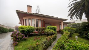 Una casa con techo curvo, entrada pavimentada y setos bien cuidados.