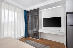 A modern hotel room with a bed, a TV mounted on the wall, a wardrobe, and a sliding glass door closet. - Beachfront Paradise 189/381 (Choeng Thale)