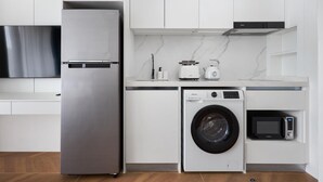 Een moderne keuken met een roestvrijstalen koelkast, een wasmachine, een magnetron en een broodrooster.