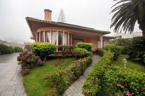A house with a curved roof, a paved driveway, and well-maintained hedges. - Room 'Quarto Belo Dia' with Shared Terrace, Wi-Fi and Air Conditioning (Cabouco)