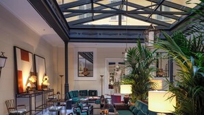 A spacious interior with a high ceiling, a central seating area with green upholstered sofas, and a checkered floor.