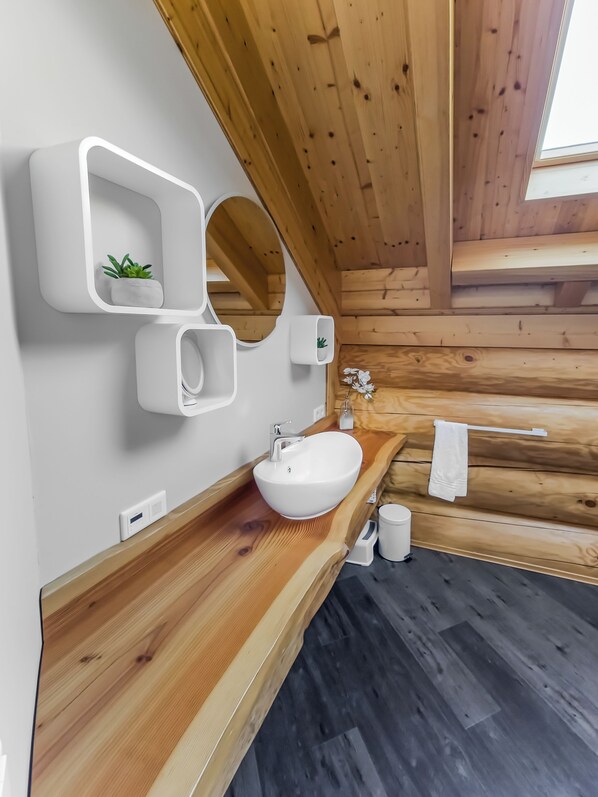 A modern bathroom with a wooden ceiling, a white sink, and a mirror.