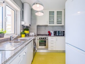 A modern kitchen with a granite countertop, stainless steel appliances, and a yellow floor. - Apartment  by Interhome (Albufeira)