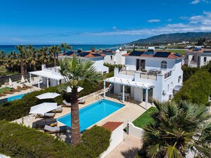 Eine Küstenvilla mit Pool, mehreren Balkonen und Meerblick.