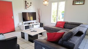 Un salon avec un canapé, une table basse, un téléviseur et une porte rouge.