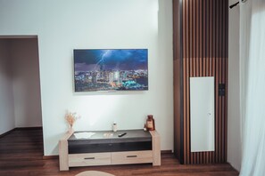 Ein modernes Zimmer mit Stadtbildgemälde, einem Holzkonsolentisch und einer Tür mit vertikalen Holzlatten.