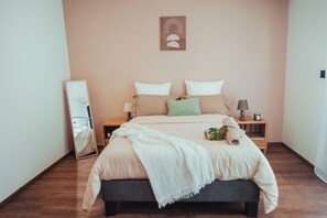 Ein Schlafzimmer mit einem Bett, Nachttischen, einem Spiegel und einem an der Wand befestigten Kunstwerk.