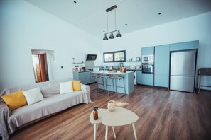 Eine moderne Küche mit Barhocker, einem Esstisch und einer Couch mit gelben Kissen.