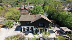 Ein traditionelles Chalet mit Steinfassade, einer Holzveranda und Blick auf ein Bergdorf.