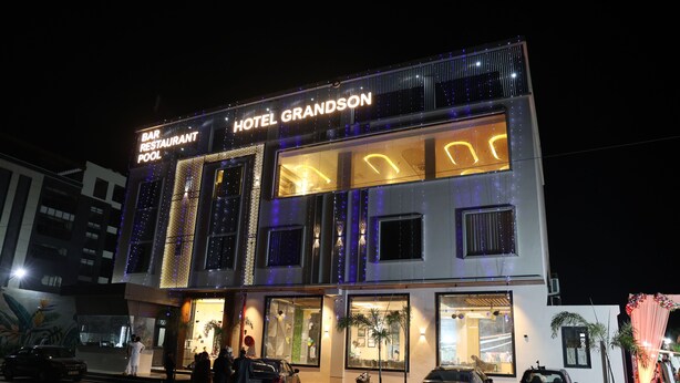 A hotel with a bar and restaurant, multiple windows, and a well-lit entrance. - VANU GROUP OF HOTEL - GRANDSON (Jaipur)