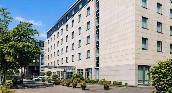 Ein modernes Hotelgebäude mit flacher Fassade, zahlreichen Fenstern und einem überdachten Eingangsbereich.