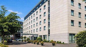 Een modern hotelgebouw met een platte gevel, meerdere ramen en een overdekte entree.