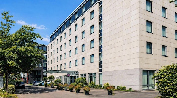 Ein modernes Hotelgebäude mit flacher Fassade, zahlreichen Fenstern und einem überdachten Eingangsbereich.