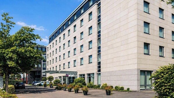 Ein modernes Hotelgebäude mit flacher Fassade, zahlreichen Fenstern und einem überdachten Eingangsbereich.