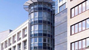 Un bâtiment moderne doté d’une façade en verre incurvée, de nombreuses fenêtres et d’une conception d’angle originale.