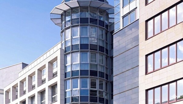 Een modern gebouw met een gebogen glazen gevel, meerdere ramen en een hoekligging.