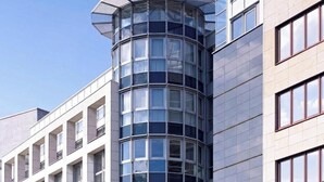 En moderne bygning med en buet glasfacade, flere vinduer og et hjørnedesign.