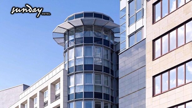 Un edificio moderno con fachada de vidrio curvo, múltiples ventanas y diseño en esquina.