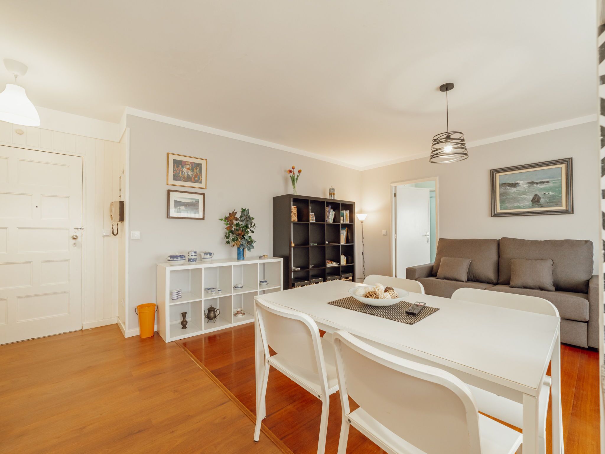 Un espacio de estar moderno con comedor, sofá y estantería.
