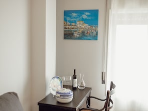 Un comedor con una mesa dispuesta para dos personas, un cuadro de una escena costera y una puerta con manija.