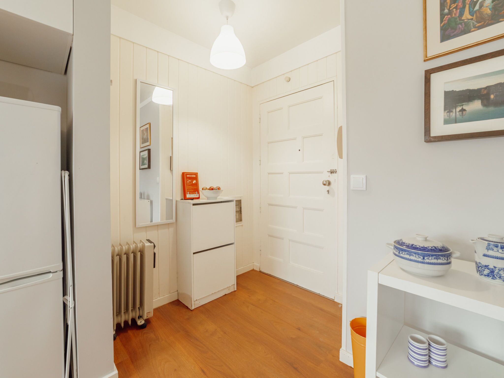 Cocina compacta con refrigerador blanco, horno integrado, gabinete blanco y piso de madera.