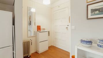Cocina compacta con refrigerador blanco, horno integrado, gabinete blanco y piso de madera.