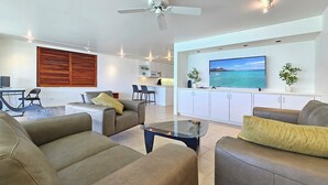Uma sala de estar moderna com um sofá, uma mesa de centro e uma TV fixada na parede.
