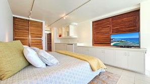 Ein modernes Schlafzimmer mit Bett, Holzläden, einem Fernseher und Blick auf den Ozean.