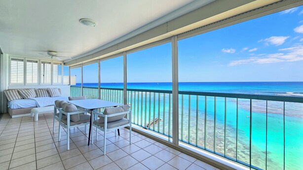 Varanda com vista para o oceano, um sofá e uma mesa.