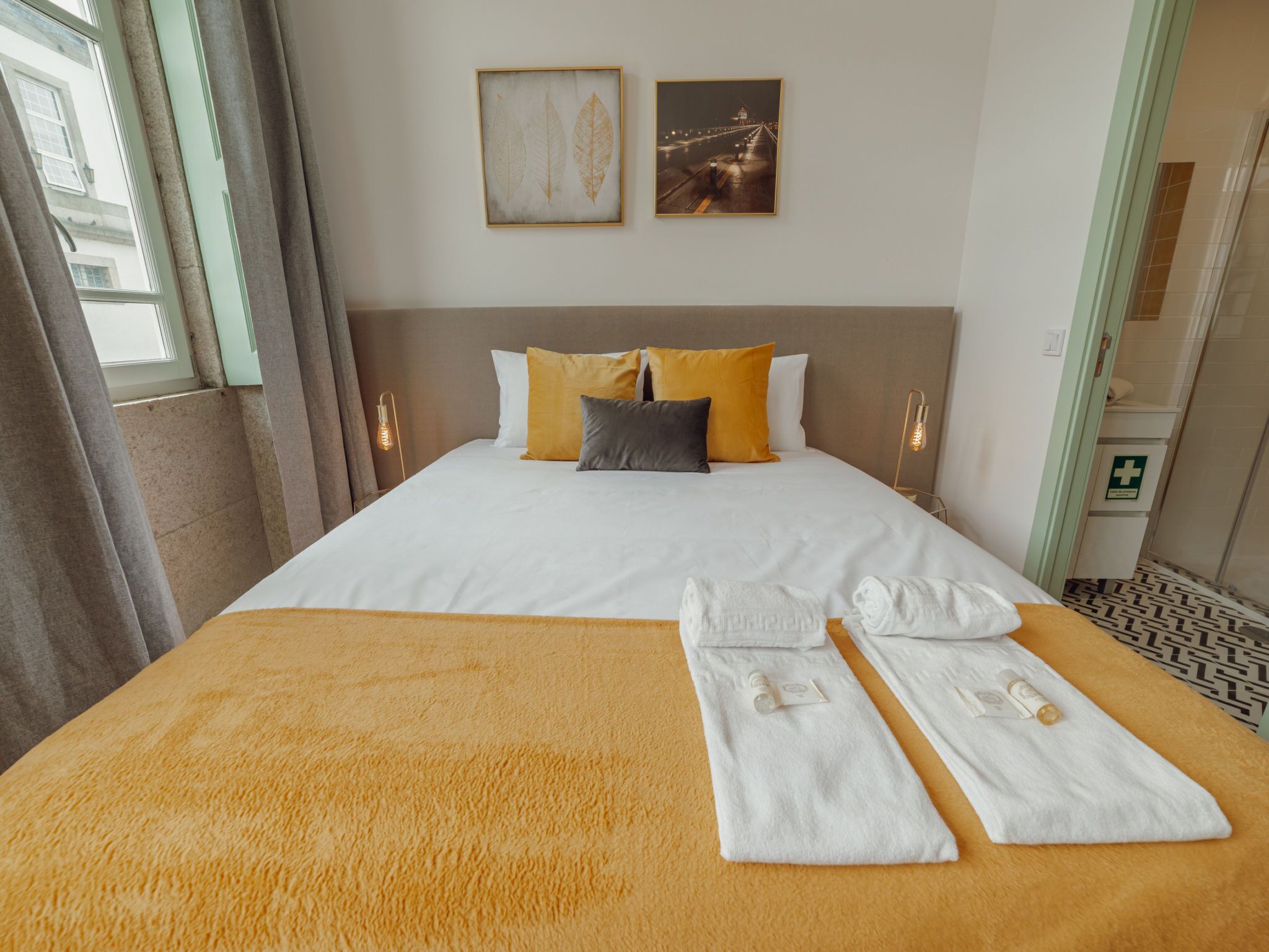 A hotel room with a bed, pillows, a blanket, and towels.