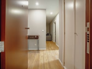 Ein Flur mit Holzboden, einer Tür mit Griff und einem an der Wand befestigten Lichtschalter.