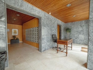 A lobby with a marble wall, a wooden ceiling, a desk, and a plant. - Apartment  by Interhome (Porto)