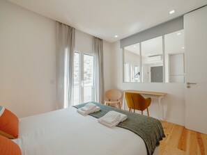 A modern hotel room with a large bed, a desk, a chair, and a view of the outdoors through the window. - Apartment  by Interhome (Porto)