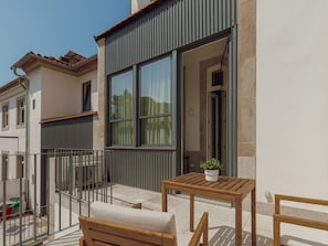 A balcony with a wooden bench and a small table, a potted plant, and a view of a neighboring building. - Apartment  by Interhome (Porto)