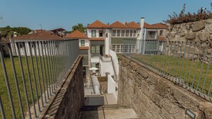 Una escalera que conduce a un edificio moderno, con un muro de contención de piedra a un lado y una valla de metal al otro.